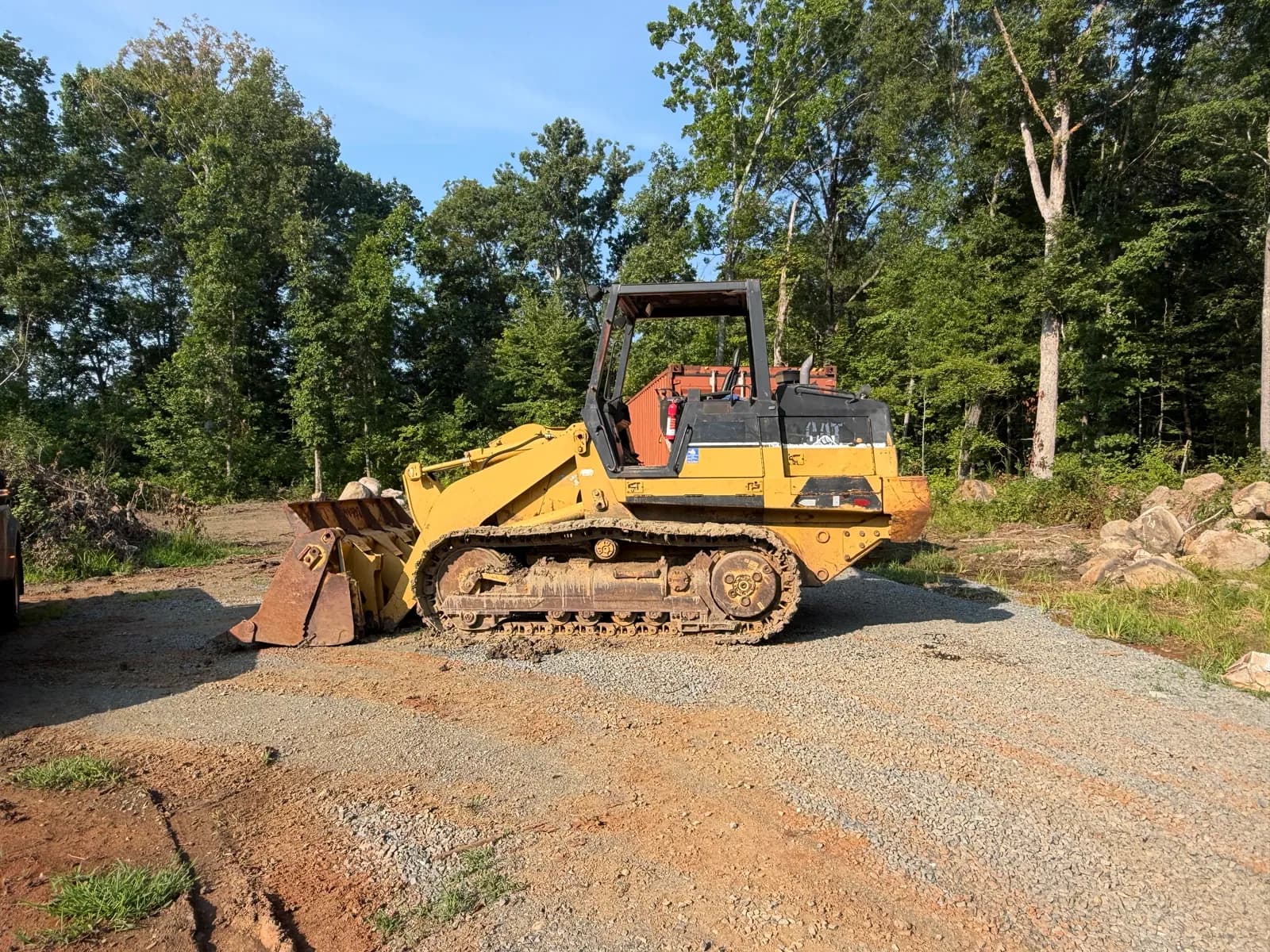 Owner-supplied photograph of a tracked loader beside woodland